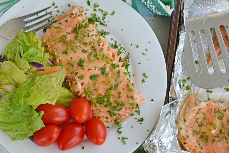 salmon filet on a white plate with salad 