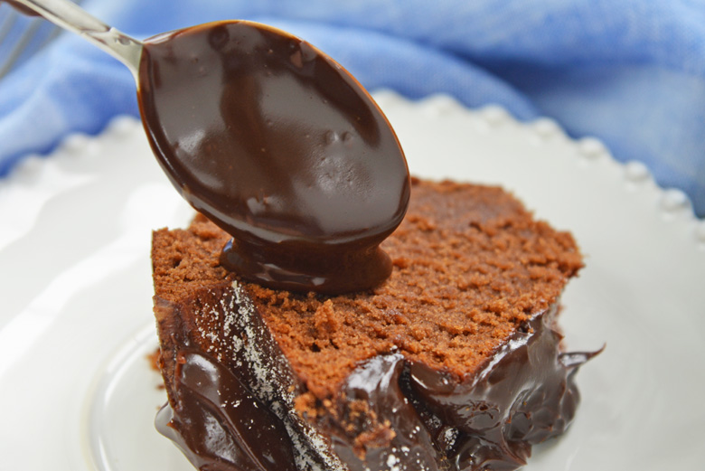 fudge sauce pouring over slice of chocolate cake 