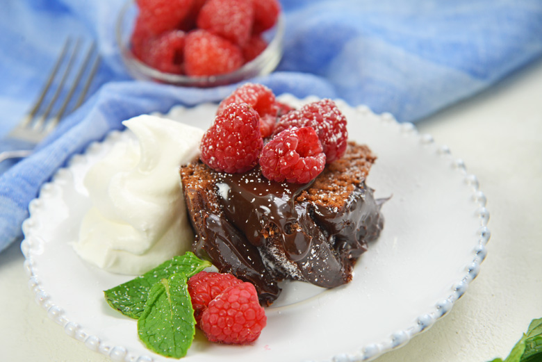 slice of chocolate bundt cake with fudge sauce, mint and raspberries 