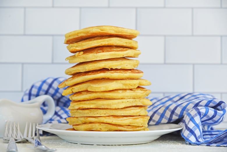 tall stack of corn cakes on white plate 