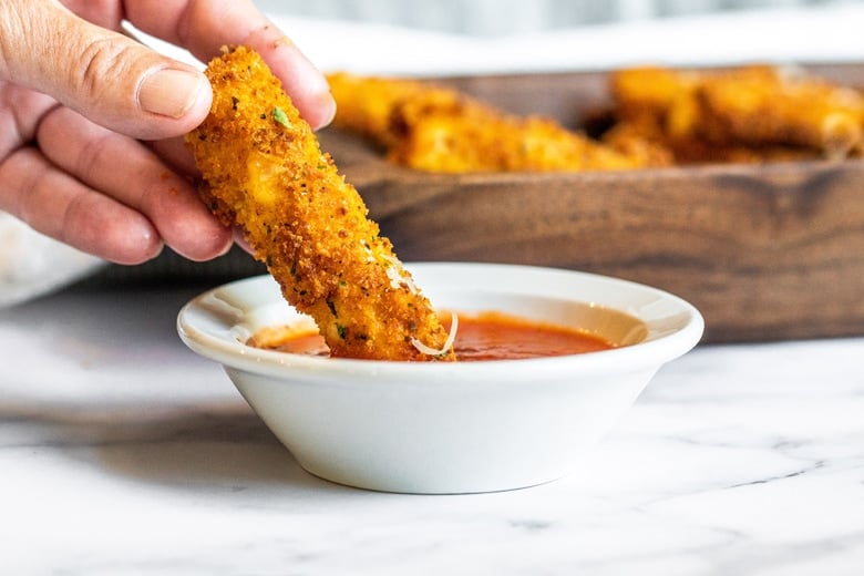 air fryer mozzarella stick dipping into sauce 