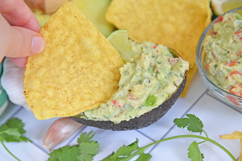 chip dipping into sour cream guacamole 