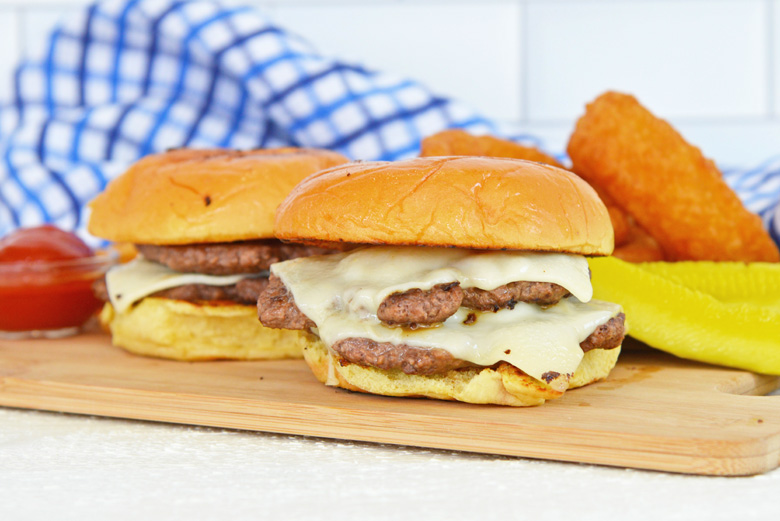 two smashburgers on a wood cutting board 