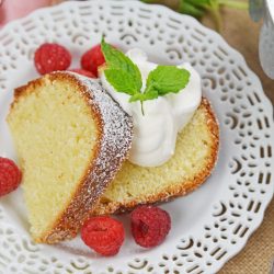 A close up of a slice of cake on a plate, with whipped cream