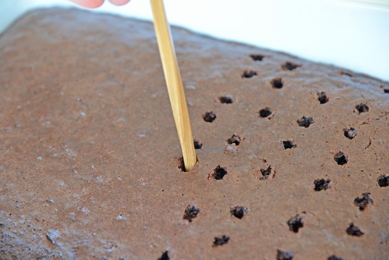 chopstick poking holes in a chocolate cake 