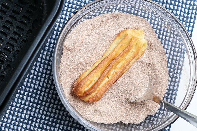 tossing churros in cinnamon sugar 