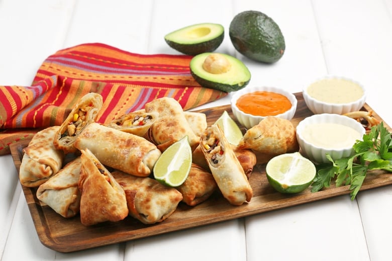 southwest egg rolls on a serving platter with dipping sauces 