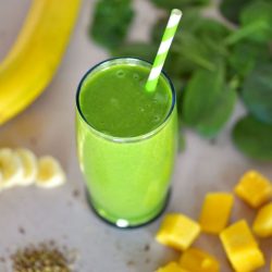 angled shot of green smoothie with straw