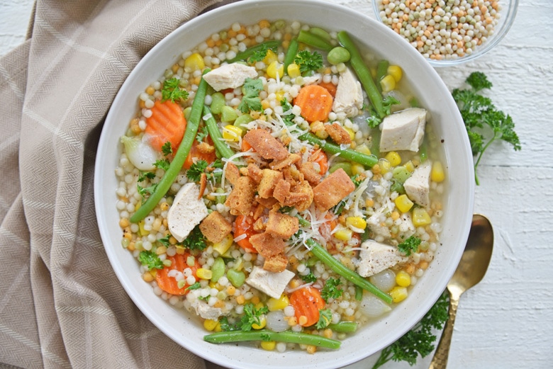 overhead bowl of turkey noodle soup with parmesan cheese and croutons 