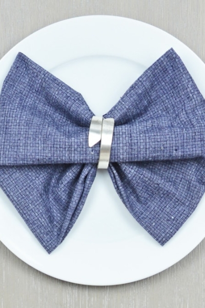 bow tie napkin fold on a blue napkin