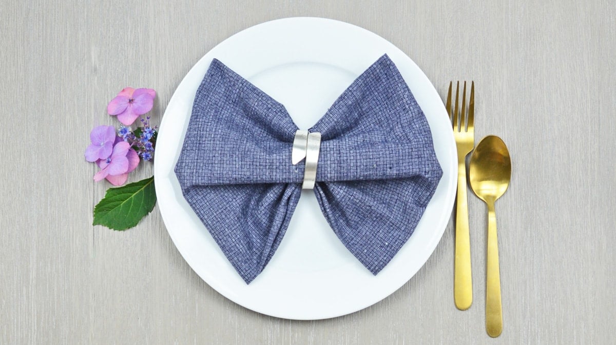 bow tie napkin fold on a blue napkin