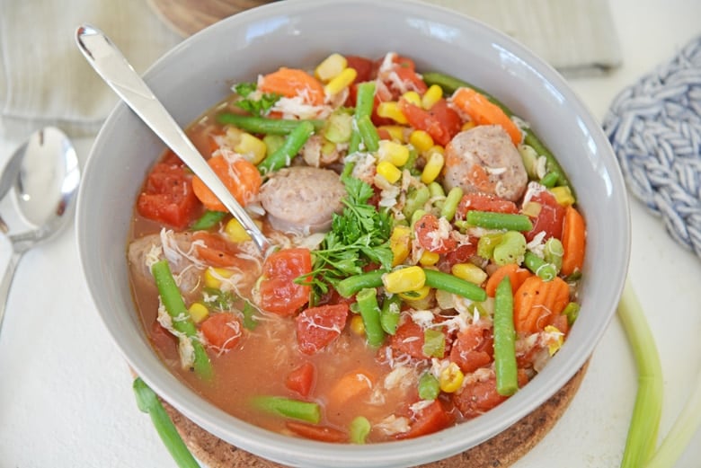 gray bowl of vegetable and crab soup with a spoon 