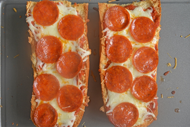 two slices of pepperoni french bread pizza on a baking sheet 