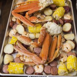 angled shot of crab legs on sheet pan with potatoes and corn