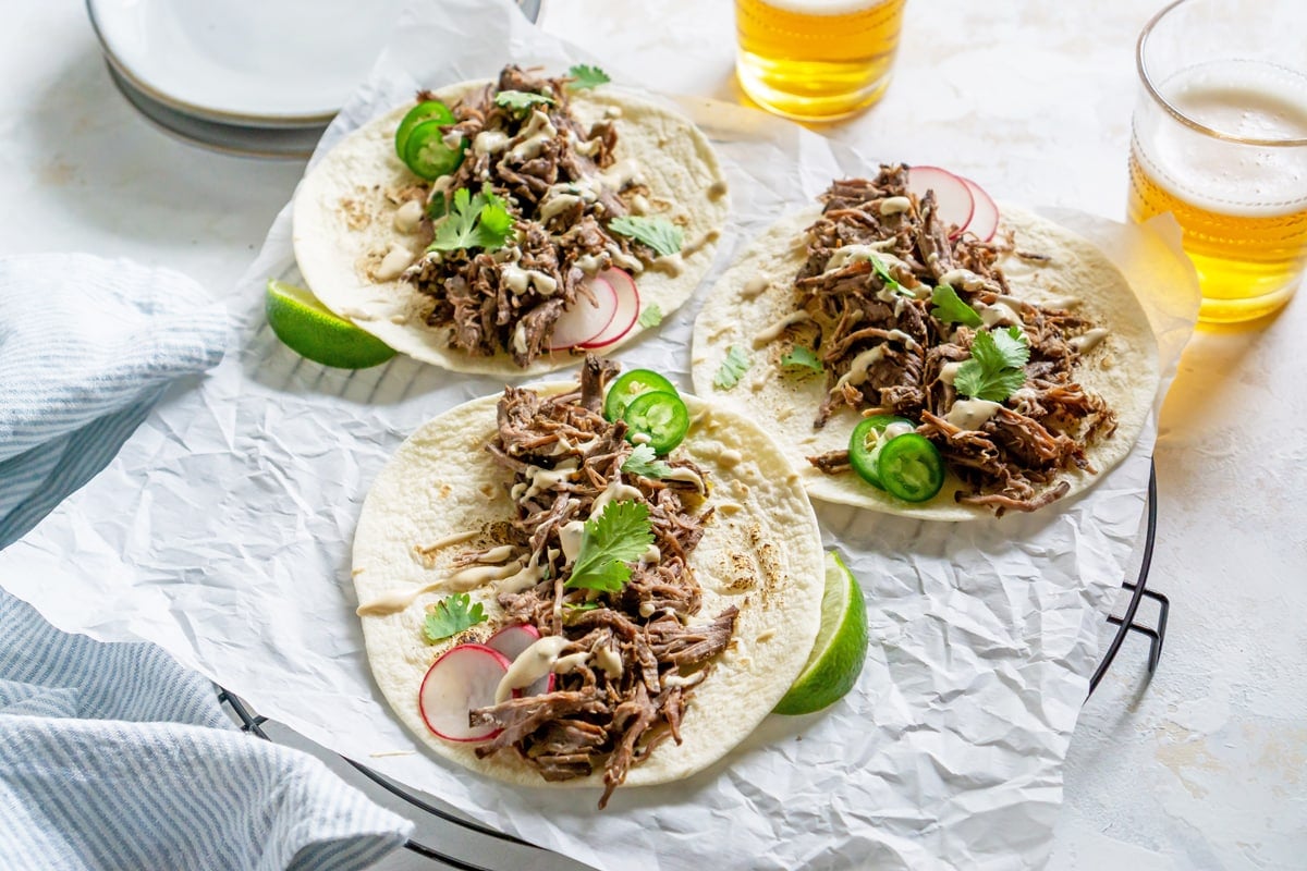 three shredded beef barbacoa tacos with beer 
