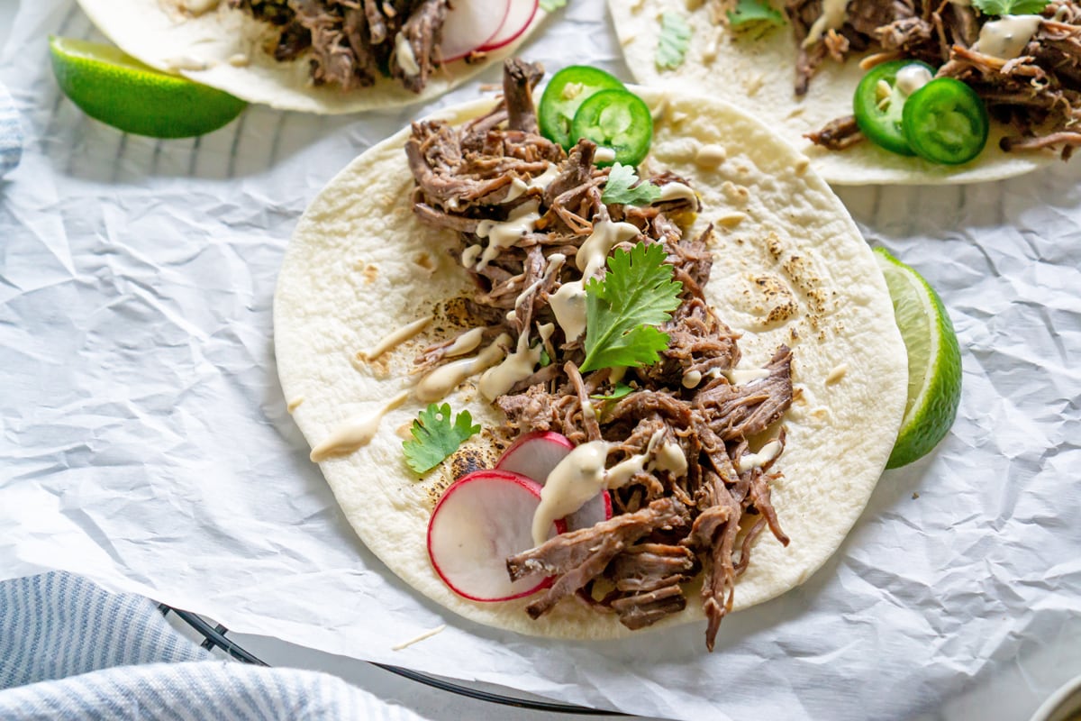 close up of beef barbacoa taco on flour tortilla 