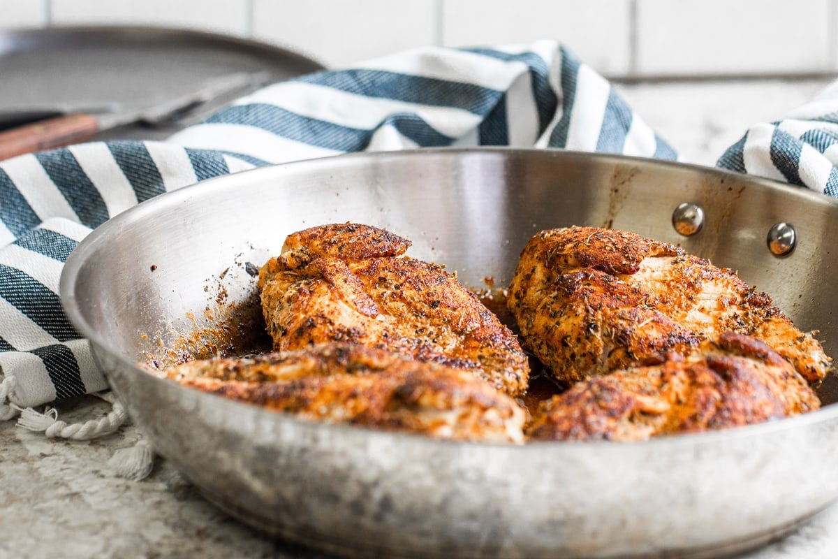 angle of blackened chicken in a frying pan  