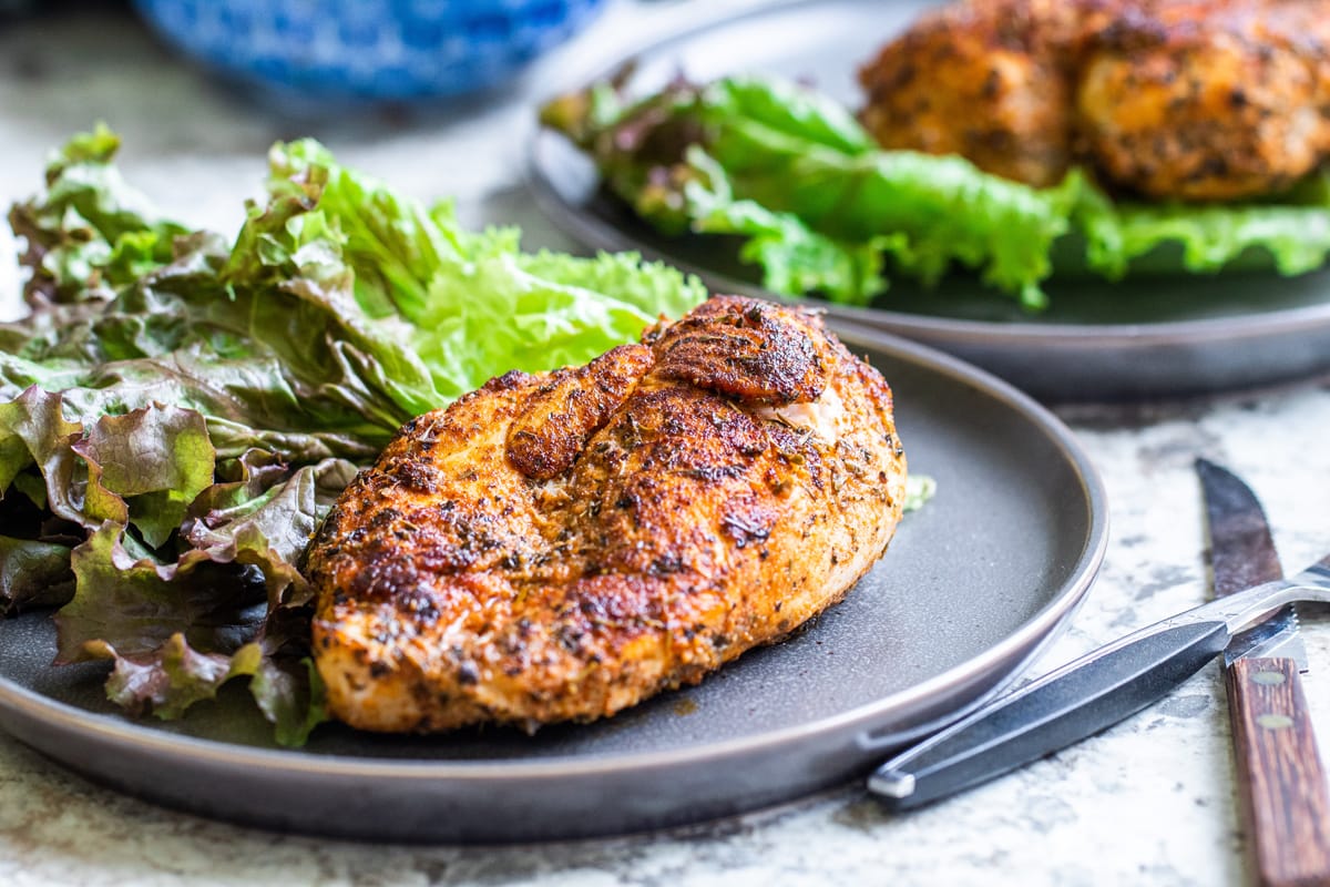 close up angled shot of blackened chicken on plate with lettuce