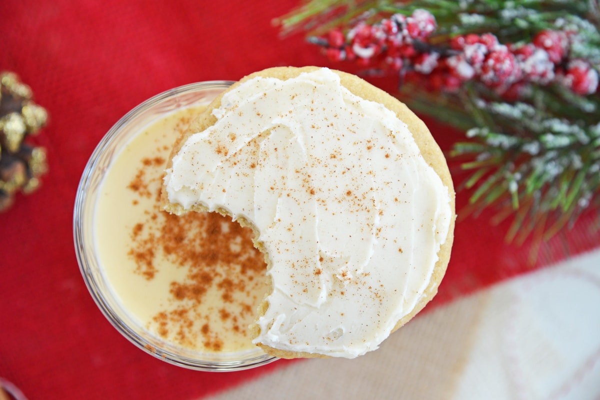 cookie with a bite missing balancing on a glass of eggnog