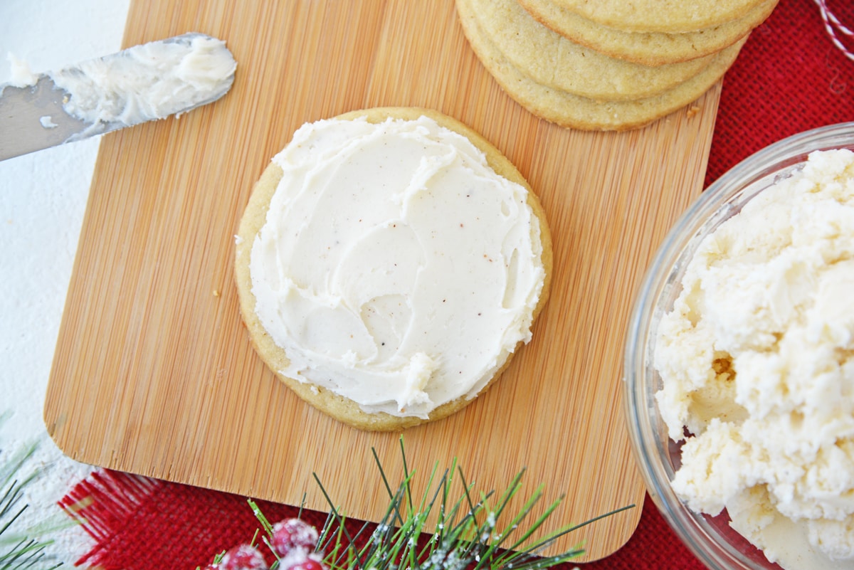 overhead of frosted eggnog cookie on a wood cutting board 