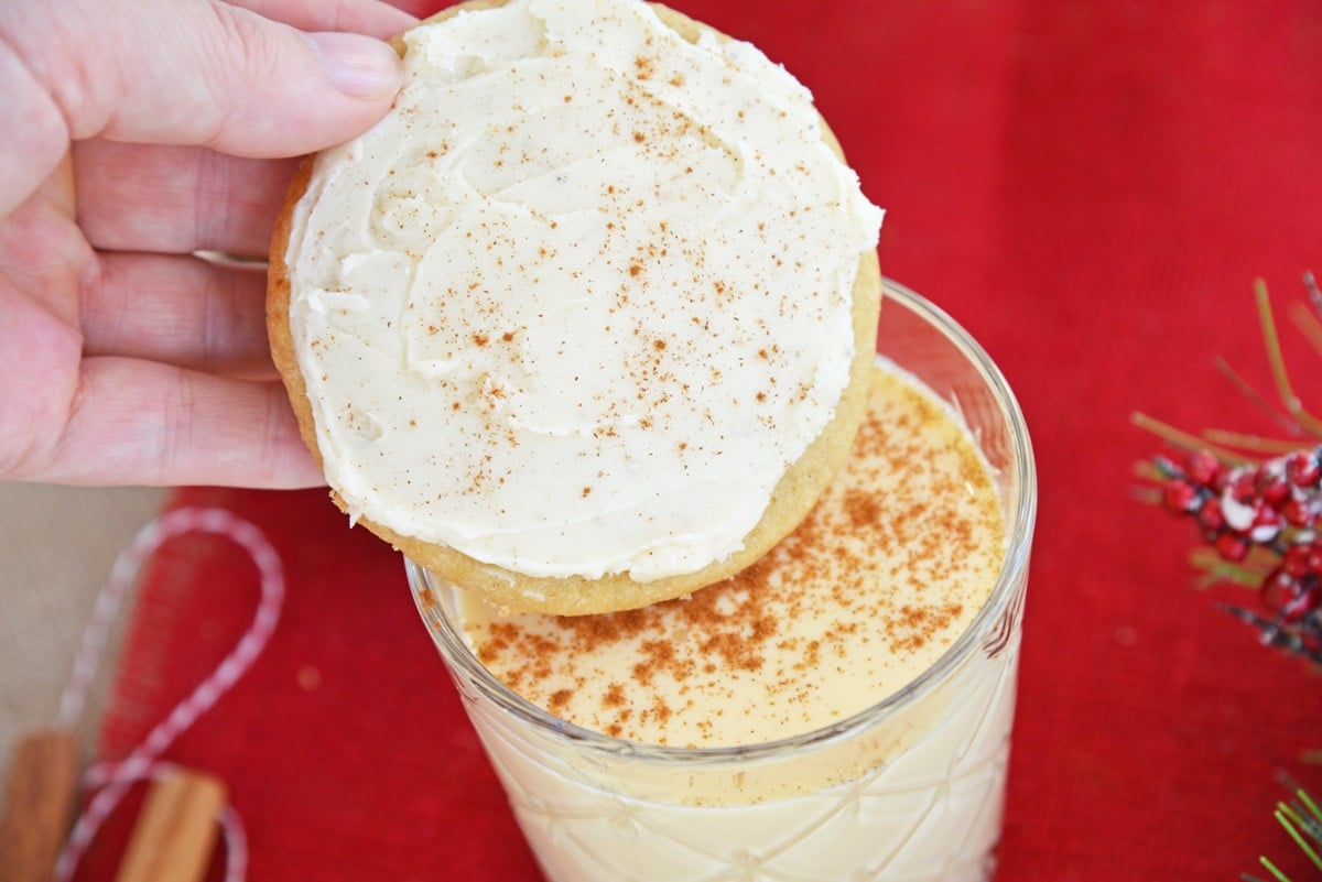 eggnog cookie dipping into a glass of cinnamon eggnog 