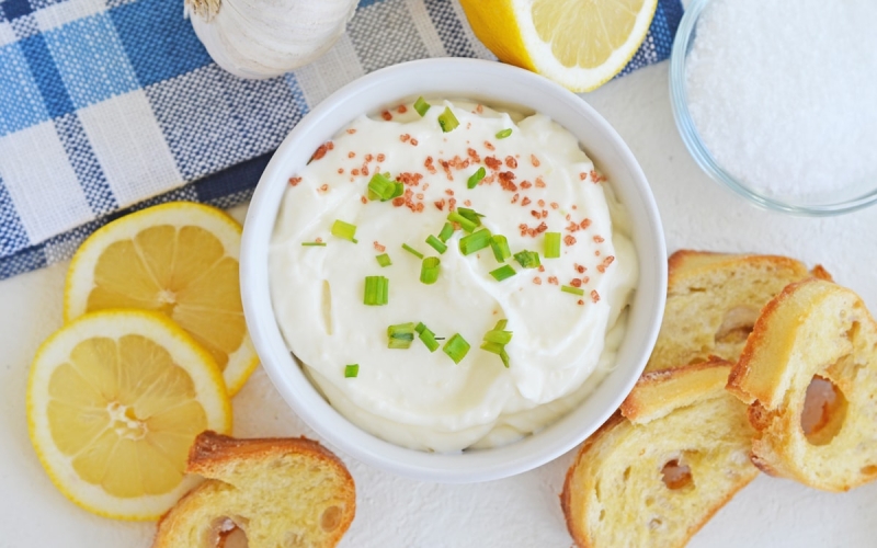 overhead bowl of garlic aioli with lemons and crostini