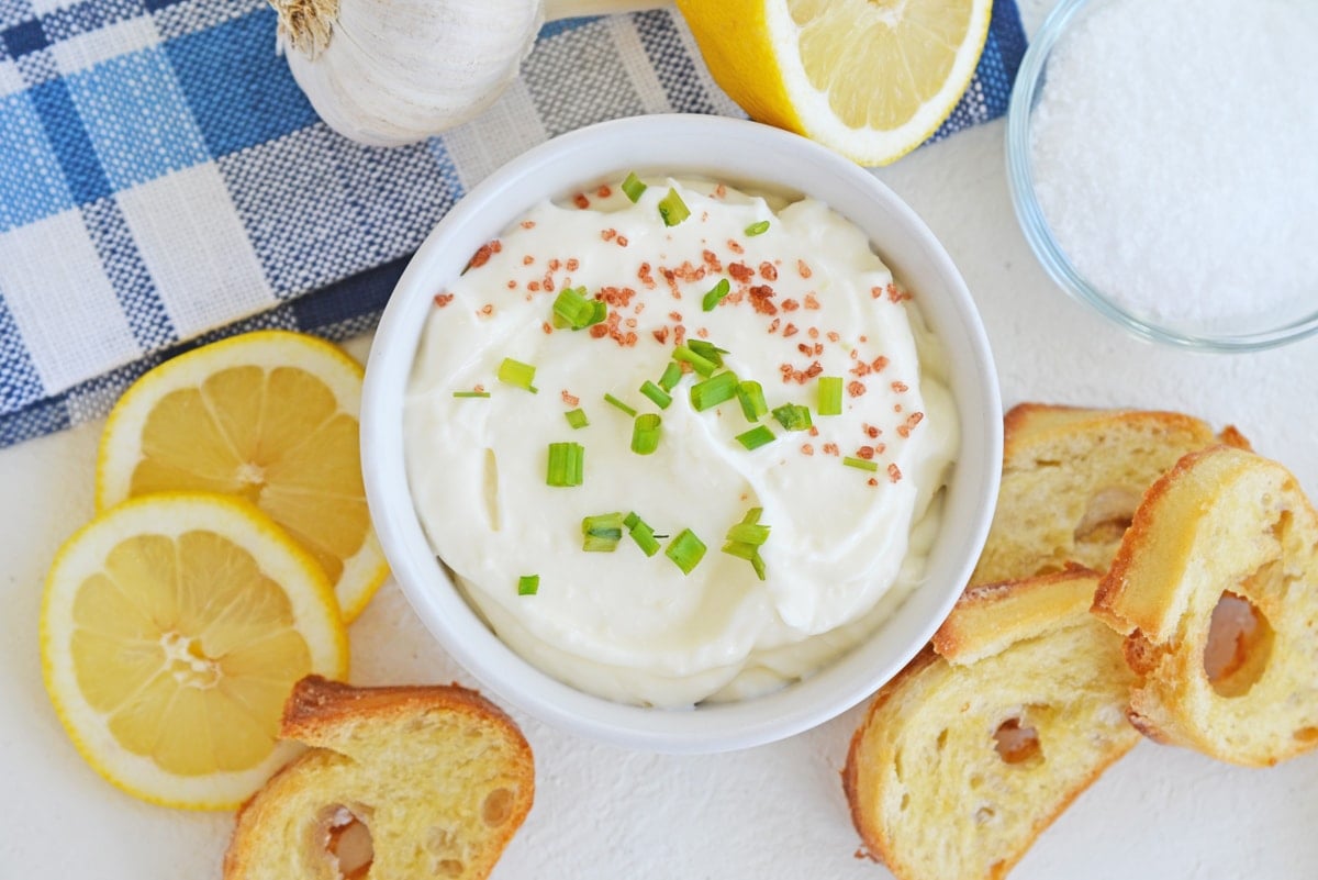 overhead bowl of garlic aioli with lemons and crostini