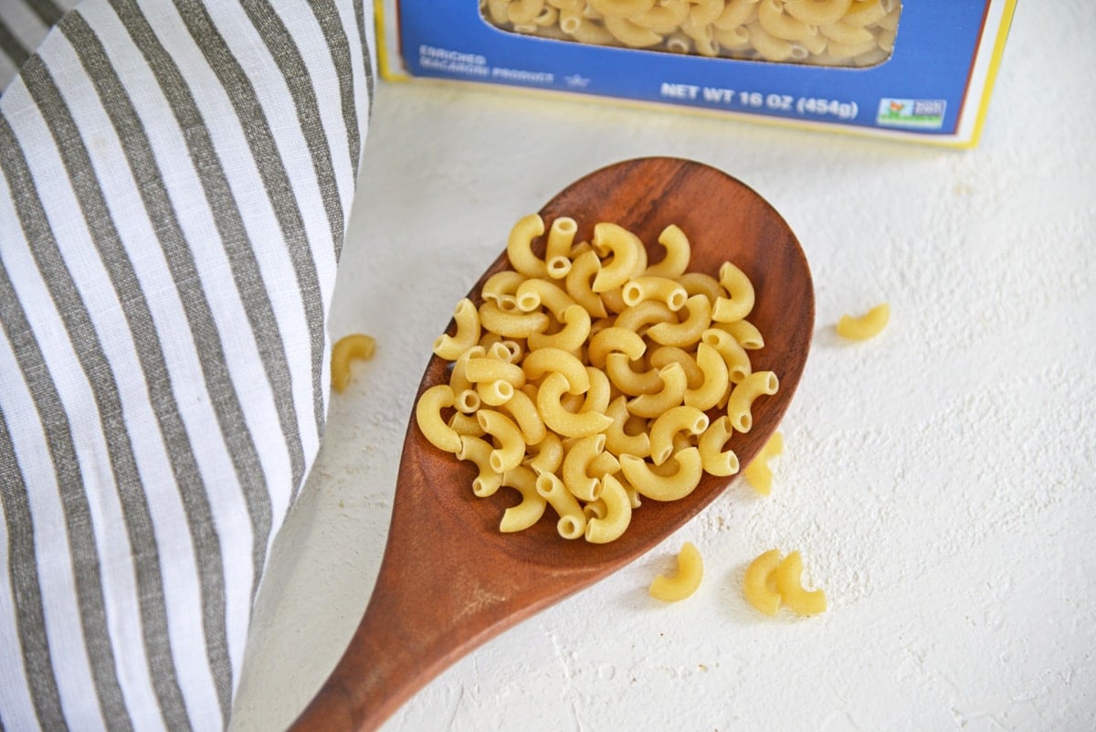 dry elbow pasta in a wooden spoon 