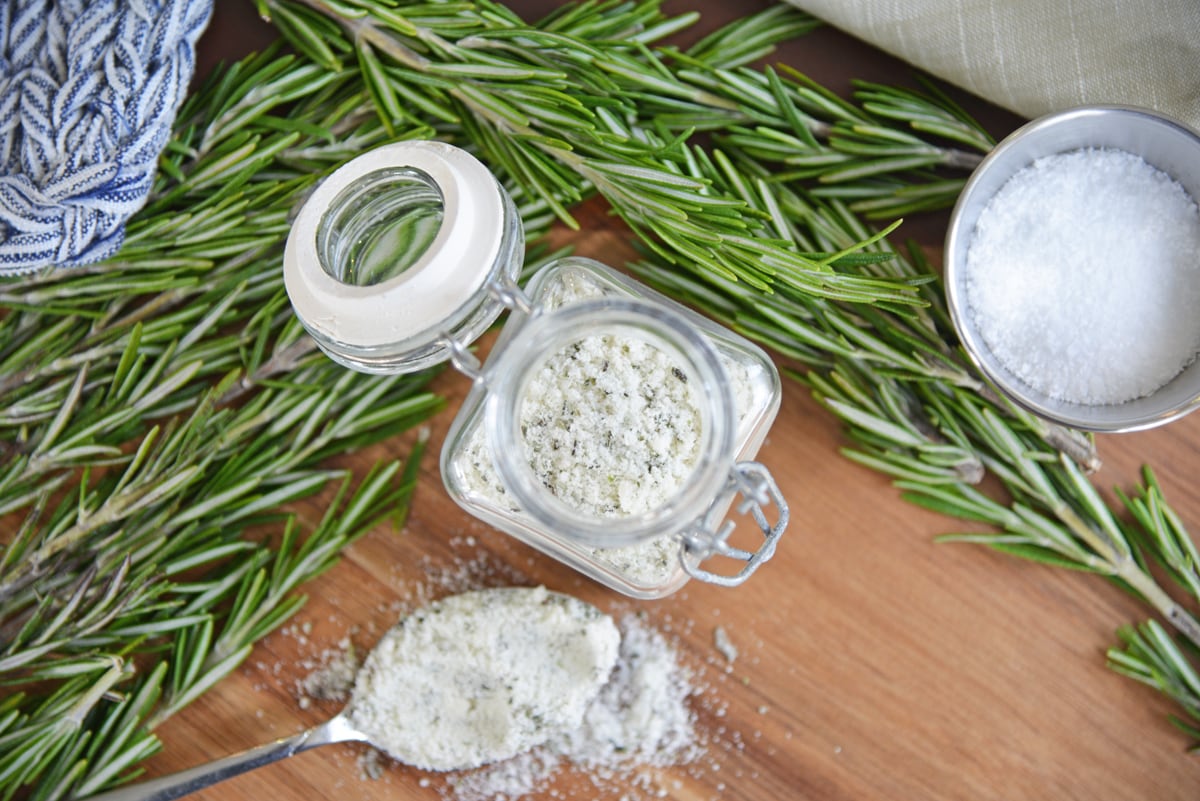 overhead of rosemary salt in a glass jar with a spoon 