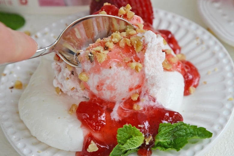 spoon digging into ice cream with topping  