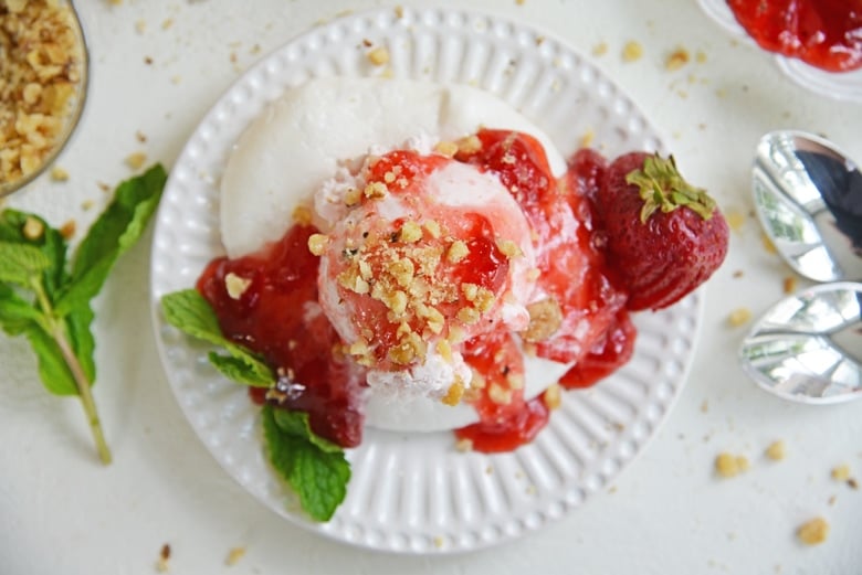 overhead of ice cream and meringue with topping, nuts and mint 