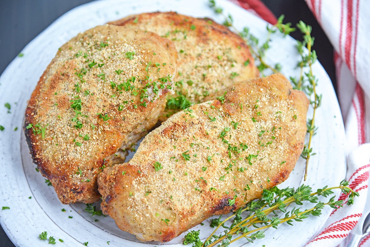 white serving plate of shake and bake pork chops garnished with fresh herbs