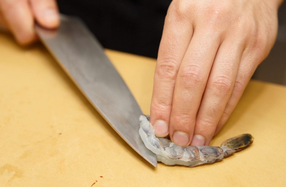 hand deveining a shrimp. 