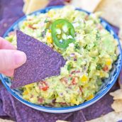 blue corn tortilla chip dipping into guacamole dip