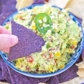 blue corn tortilla chip dipping into guacamole dip