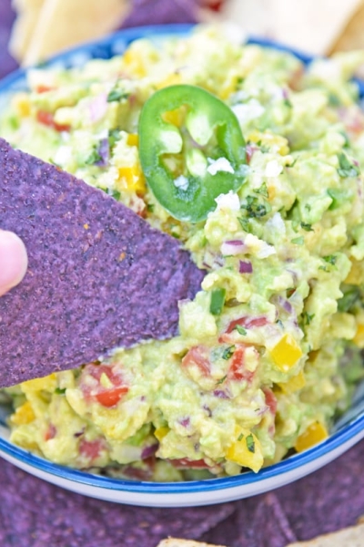 blue corn tortilla chip dipping into guacamole dip