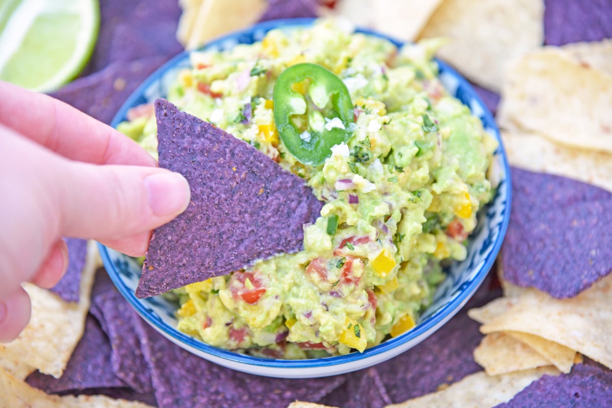 blue corn tortilla chip dipping into guacamole dip