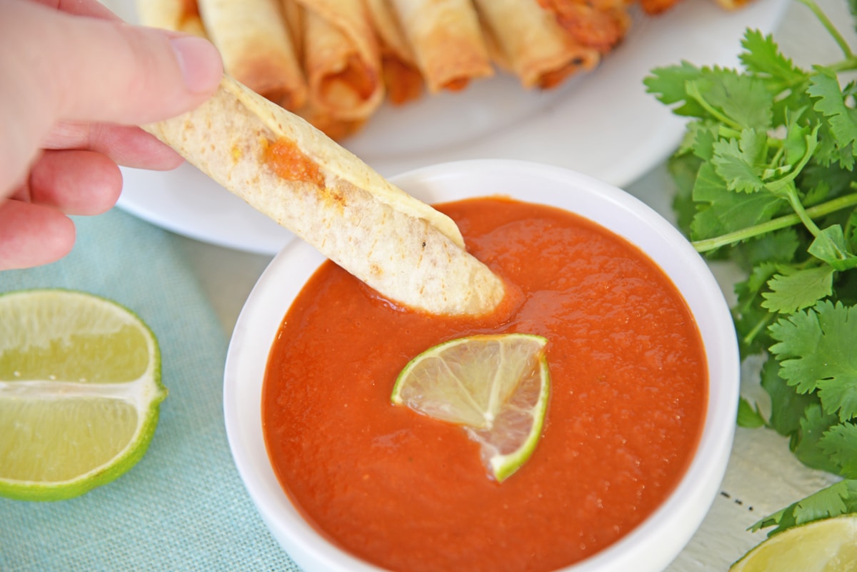chicken taquito dipping into ranchero sauce 
