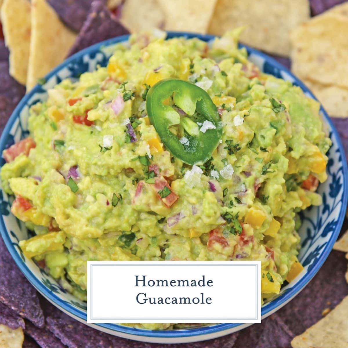 blue bowl of homemade guacamole garnished with a jalapeno slice 