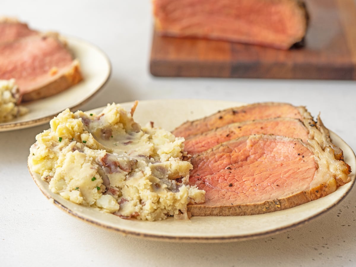 sliced of roast beef on a plate with mashed potatoes 