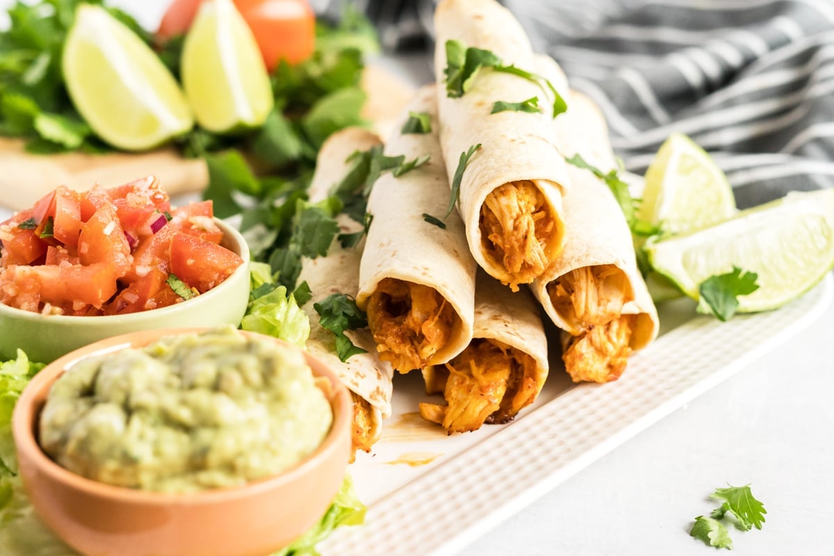 angle showing inside of rolled chicken taquitos with sauces 