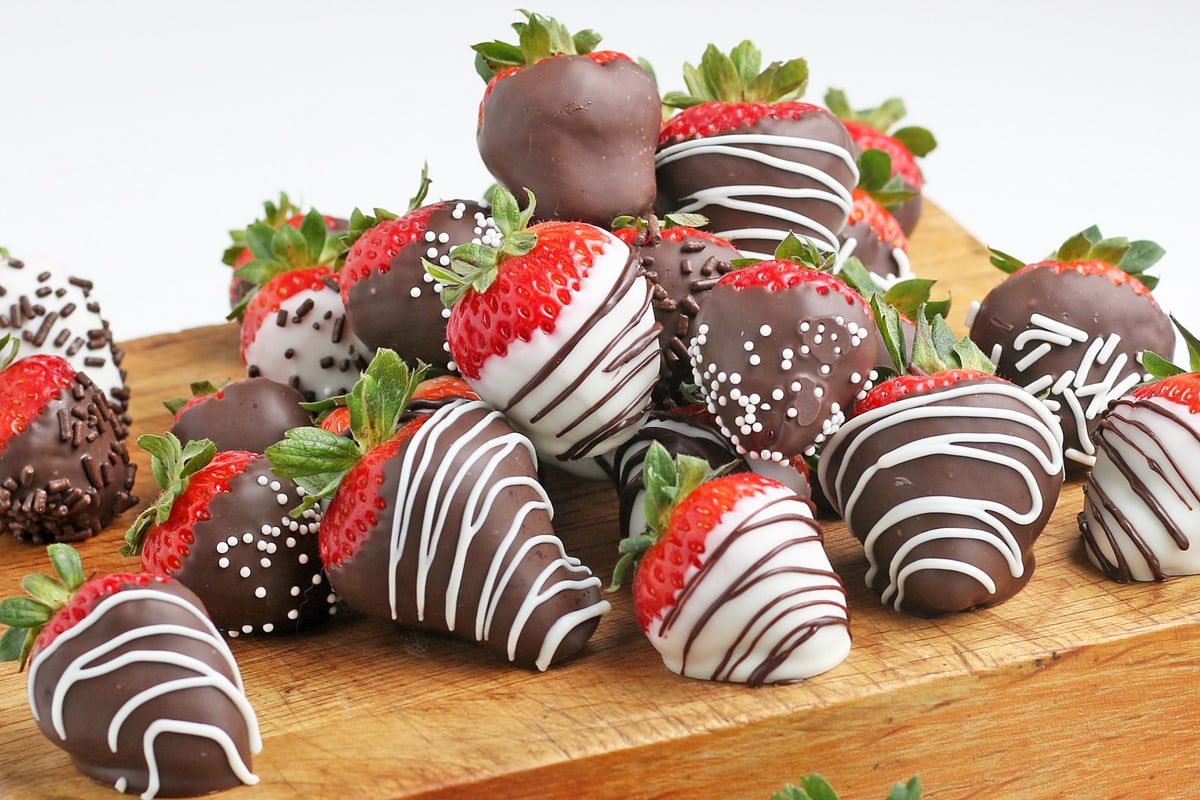 pile of chocolate dipped strawberries on a cutting board 