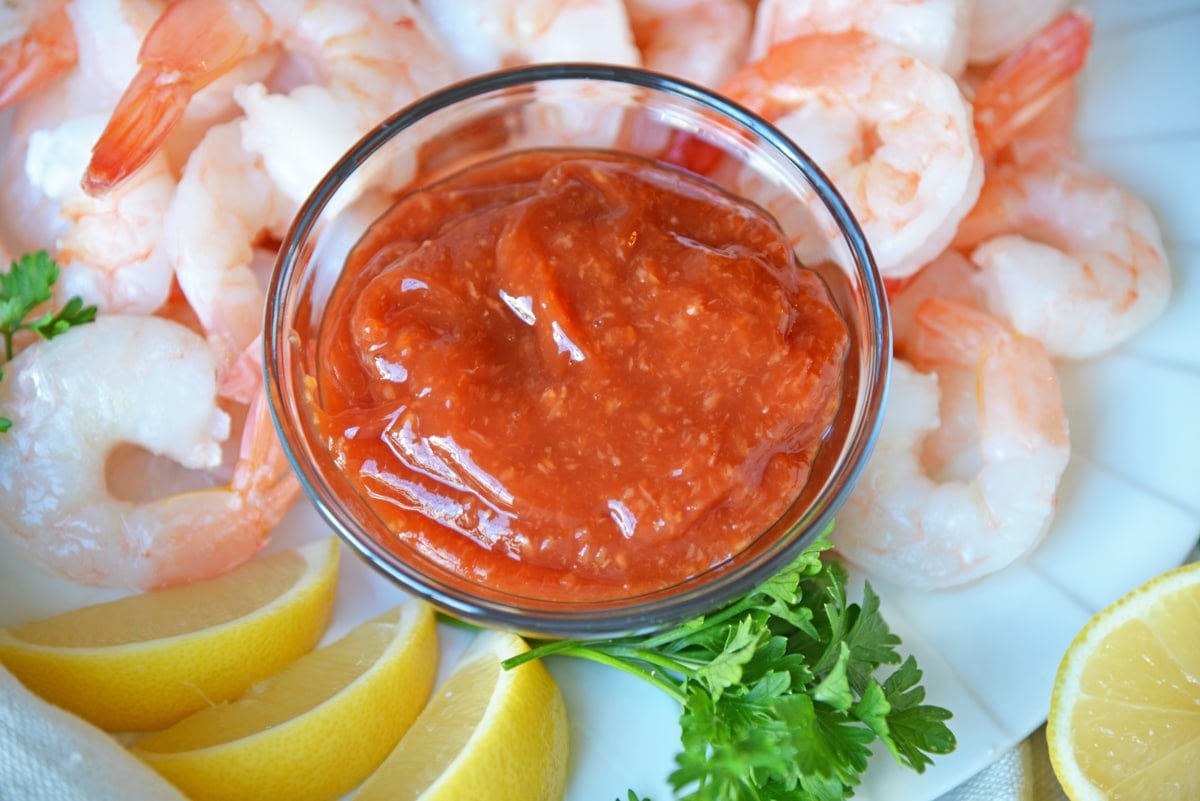 angle of homemade cocktail sauce, lemons and steamed shrimp 