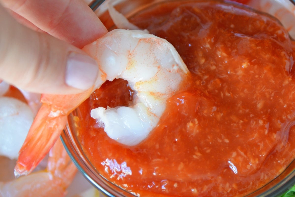 shrimp dipping into homemade cocktail sauce 