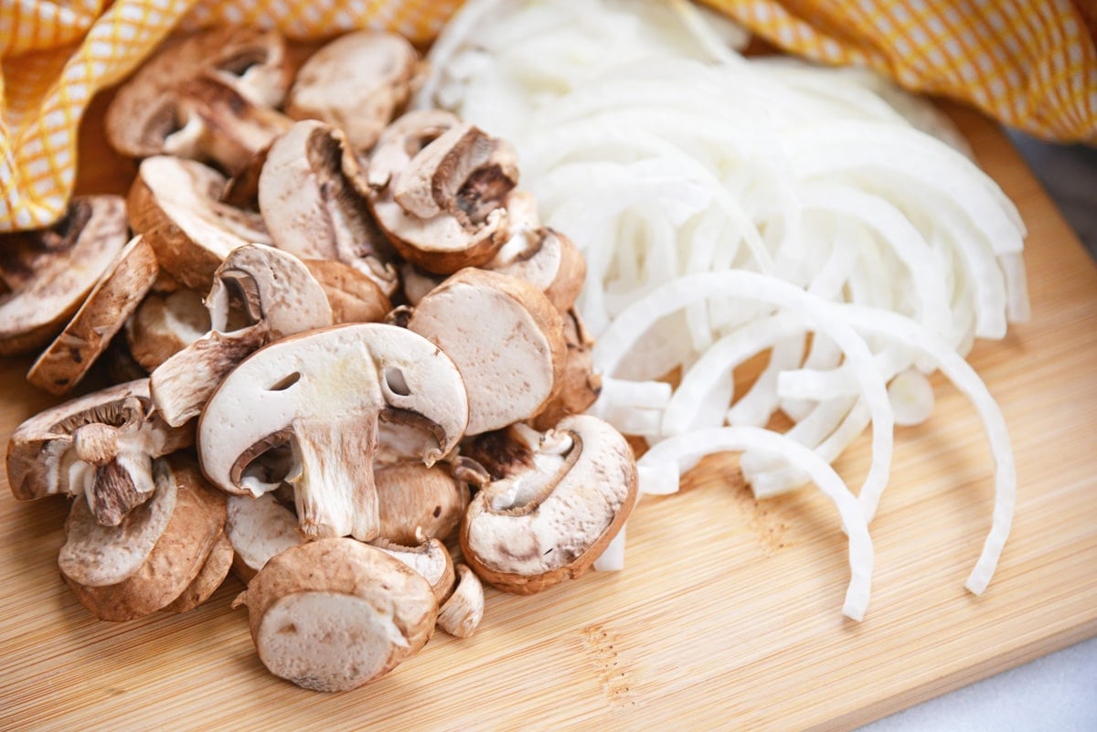 mushrooms and onions on a cutting board 