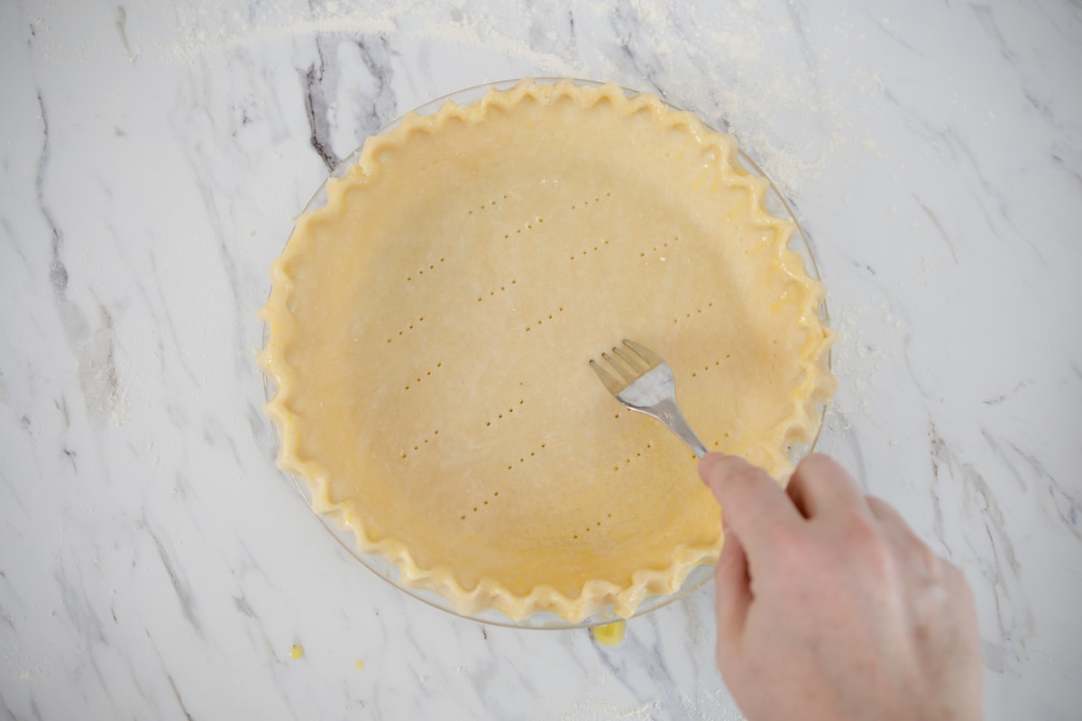 piercing unbaked pie crust with a fork 