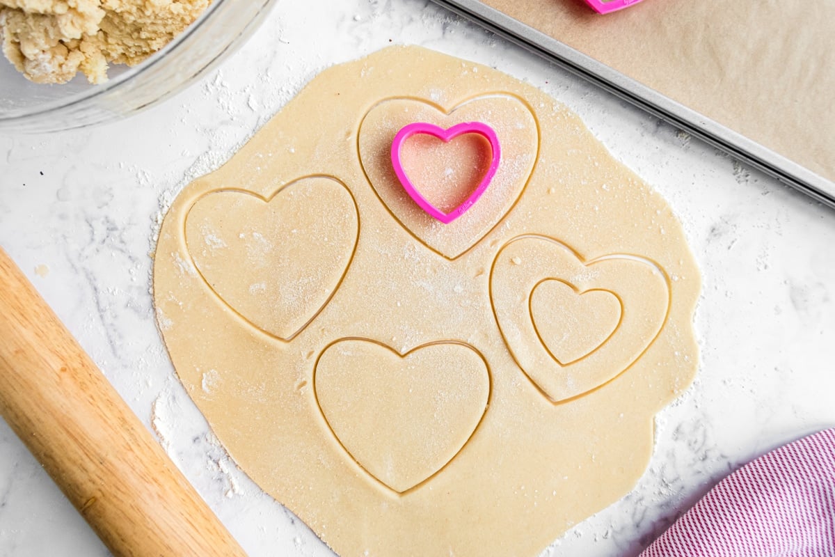 sugar cookie dough rolled out with heart shaped cookie cutters  