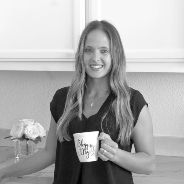 black and white image of woman holding coffee cup smiling at camera