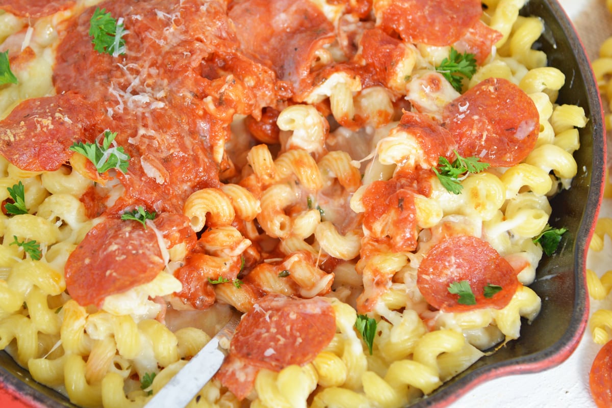 spoon digging into cast iron skillet of mac and cheese 