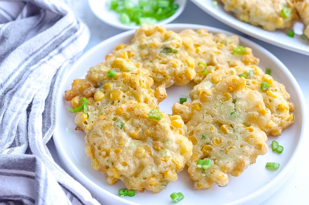 corn fritters on a white plate with scallions garnish 